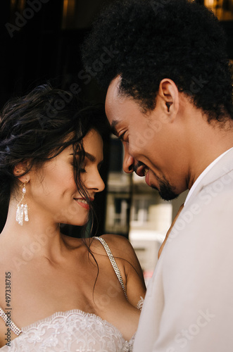 Stylish stunning couple together on their wedding day against the backdrop of a hotel in the city. Summer fashion outfits. Focus on the girl.