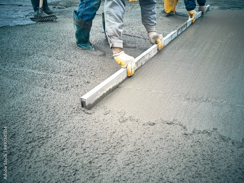 Construction worker uses trowel to level cement mortar screed. Concrete