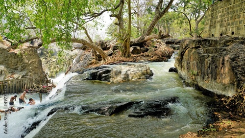 Hogenakkal,Tamilnadu,India-March 19 2022: Tourists taking bath in hogenakkal falls. Hogenakkal falls is one of the main tourist attraction of Tamilnadu, India. photo