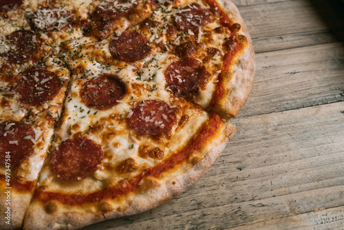 Delicious hot meat pizza with prosciutto and salami on a wooden table. High quality photo
