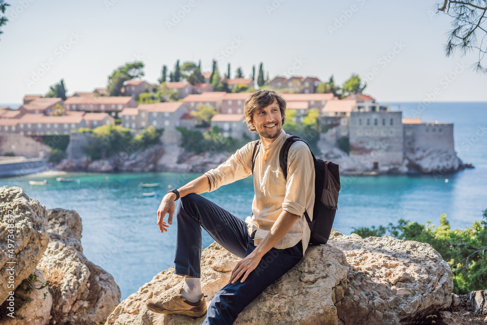 Man tourist on background of beautiful view of the island of St. Stephen, Sveti Stefan on the Budva Riviera, Budva, Montenegro. Travel to Montenegro concept