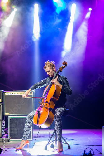 Photo Young woman playing cello on the concert at night