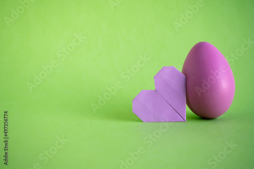 Easter egg and origami heart on green backgorund. Copy space