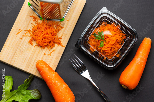 Shredding carrots with lunch box package on black table background