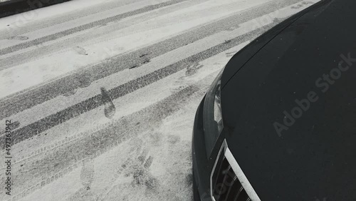 headlight of a black car on the right snow is falling winter late spring precipitation in the yard. High quality 4k footage