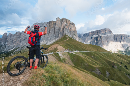 Man on cycling electric rides mountain trail. Man riding on bike in Dolomites mountains landscape. Cycling e-mtb enduro trail track. Outdoor sport activity. 