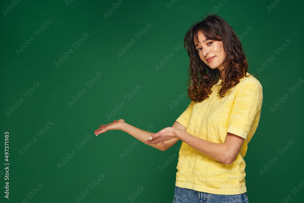 Beautiful young girl presenting advertising space on palms pointing to copy space, holding empty place for advertisement