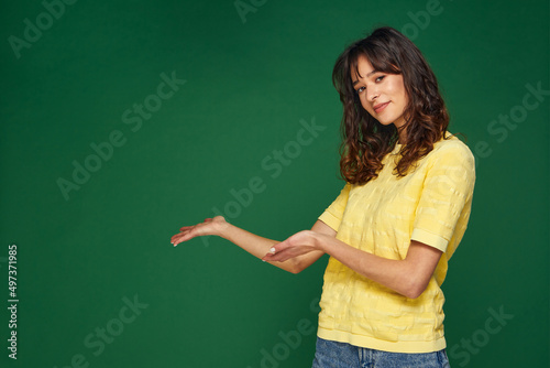 Beautiful young girl presenting advertising space on palms pointing to copy space, holding empty place for advertisement