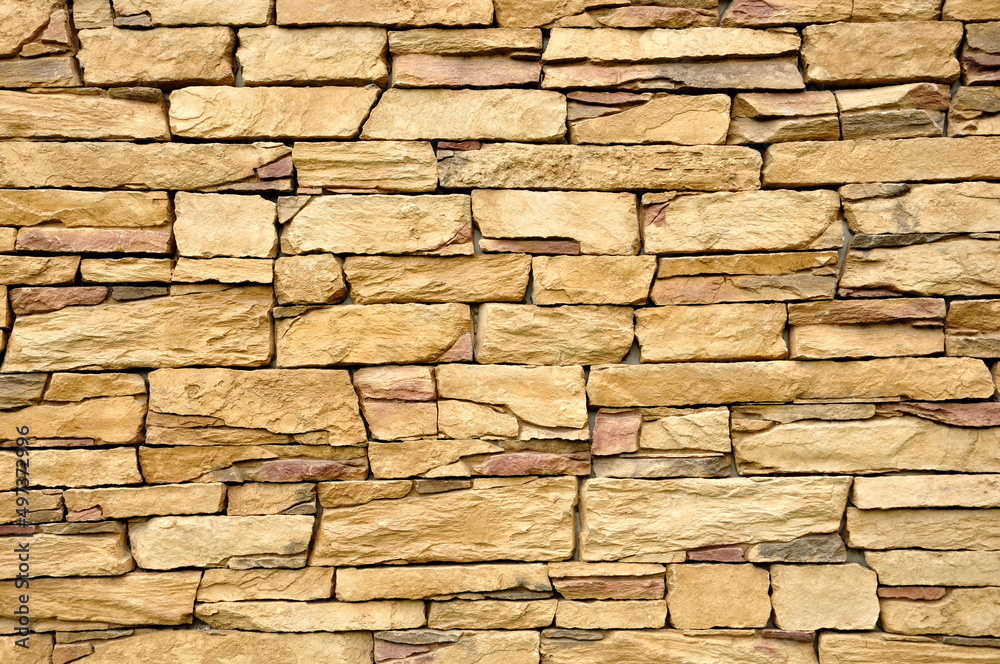 Part of the beige stone wall. Brown rock wall background texture.