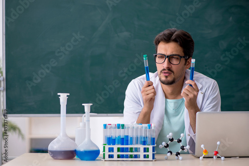 Young male chemist in front of blackboard