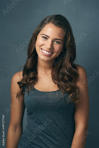 She has that youthful glow. Studio shot of a beautiful young woman posing against a blue background. © AS/peopleimages.com