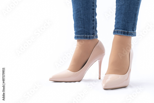 Slender female legs in patent leather shoes with high heels. Dark blue jeans. Fashion and Style. Side view
