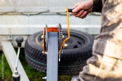 Bilde på lerret A man spins the winch handle on a car trailer