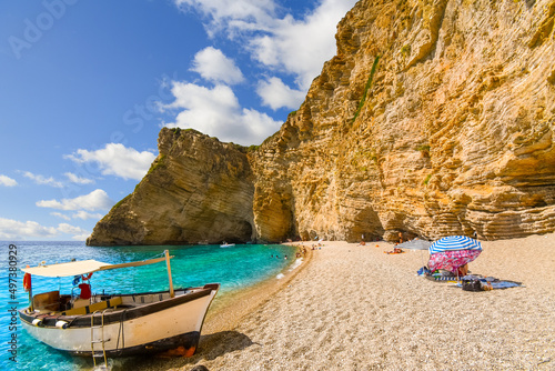 Fototapeta Naklejka Na Ścianę i Meble -  A small boat sits on the sandy shoreline at Chomi Beach also known as Paradise Beach on the island of Corfu, Greece.
