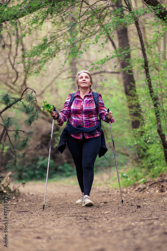 A mature woman in her 50s walks in the mountains. Use hiking poles. © DusanJelicic