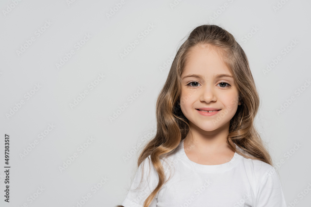 portrait of cheerful girl with long hair looking at camera isolated on grey. portrait of cheerful girl with long hair looking at camera isolated on grey.