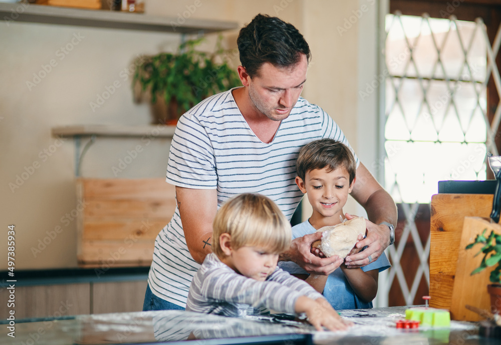 Time with his boys bakes his day. Shot of a young man baking with his two adorable sons at home.