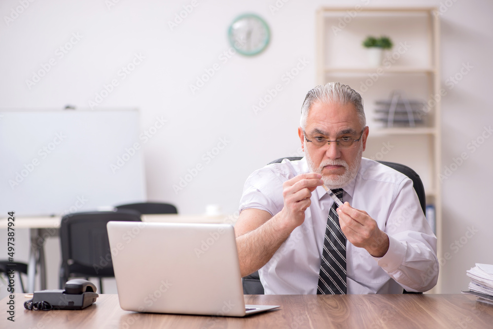 Aged male employee suffering at workplace Aged male employee suffering at workplace