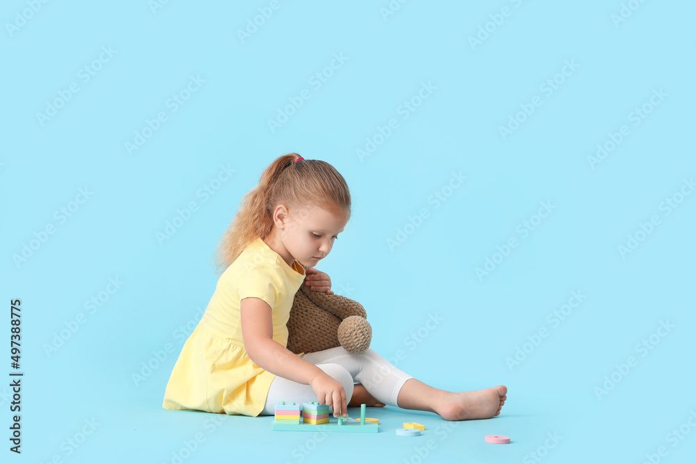 Cute little girl playing with building blocks on blue background Cute little girl playing with building blocks on blue background