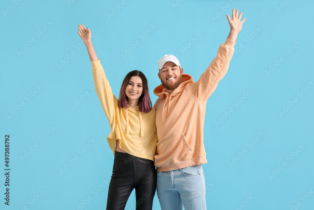 Cool happy young couple in hoodies on color background