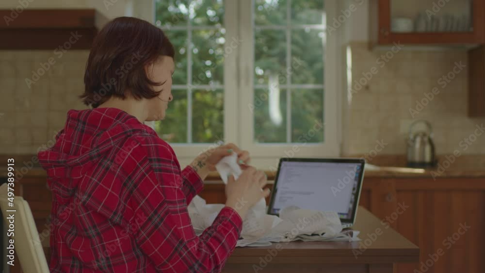 Side view of 30s woman accounting family budget and throwing store receipts sitting in the kitchen. Side view of 30s woman accounting family budget and throwing store receipts sitting in the kitchen.
