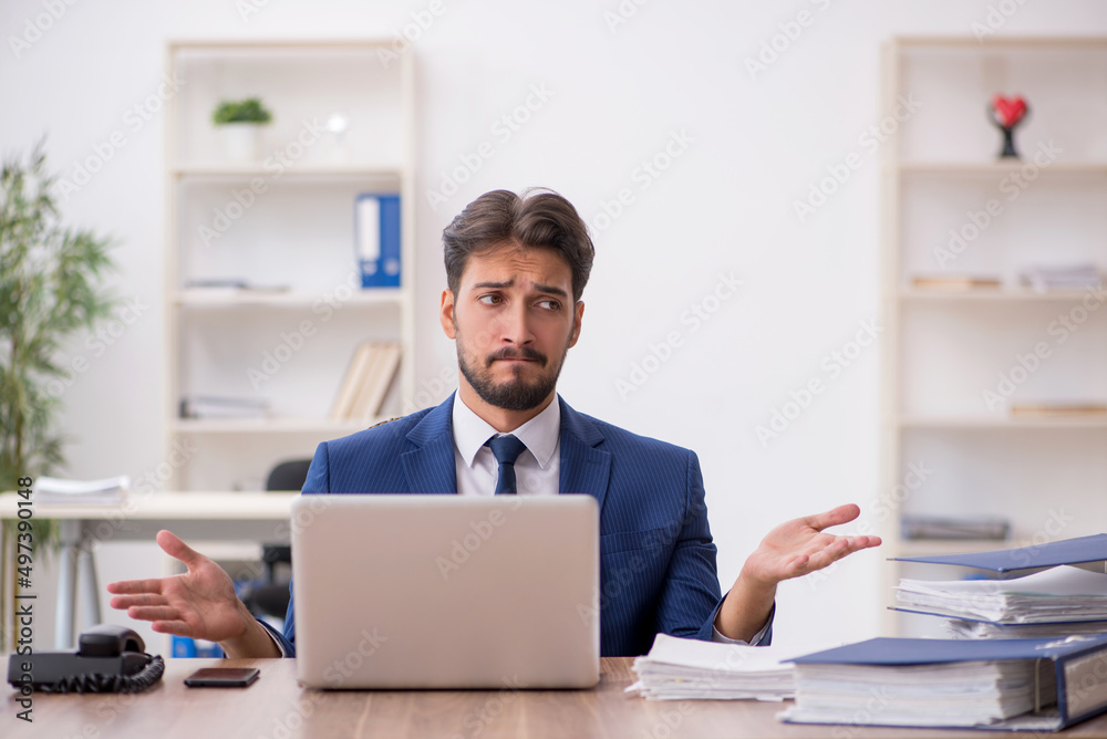 Young male employee unhappy with excessive work in the office
