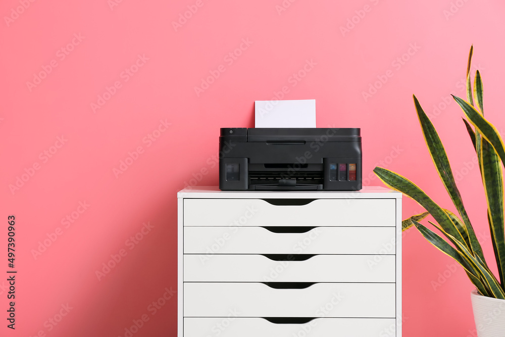 Chest of drawers with modern printer and houseplant near color wall Chest of drawers with modern printer and houseplant near color wall