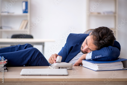 Young male employee extremely tired in the office