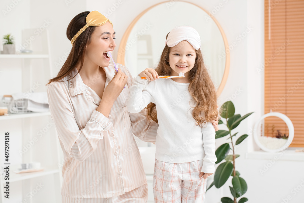 Little girl and her mother with sleeping masks brushing teeth in bathroom Little girl and her mother with sleeping masks brushing teeth in bathroom