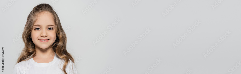 cheerful girl with long hair smiling at camera isolated on grey, banner. cheerful girl with long hair smiling at camera isolated on grey, banner.