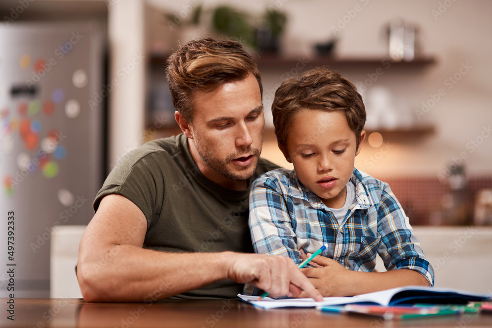 Parents are a childs first and most important teachers. Shot of a man sitting with his son while he does his homework. Parents are a childs first and most important teachers. Shot of a man sitting with his son while he does his homework.