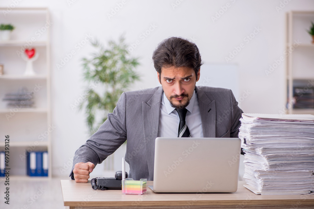 Young male employee and too much work in the office Young male employee and too much work in the office