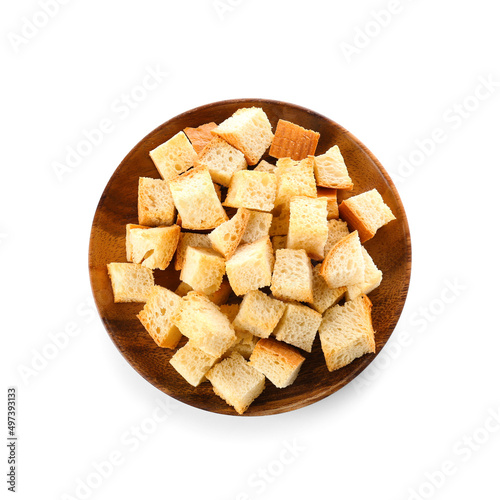 Wooden plate with crunchy croutons isolated on white, top view