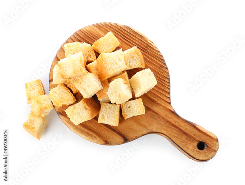 Wooden board with crunchy croutons isolated on white, top view
