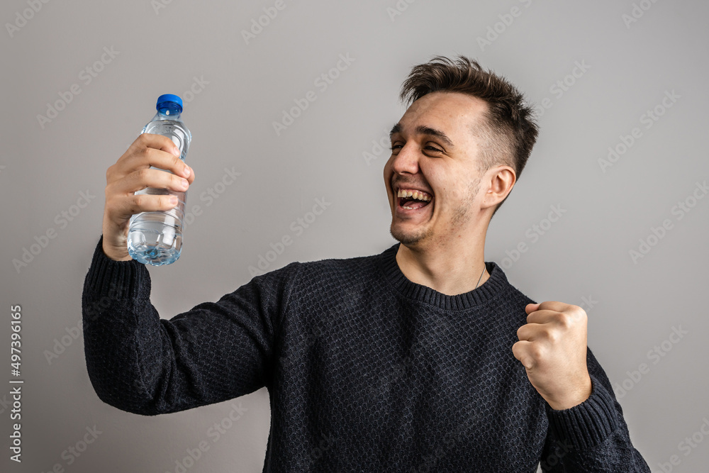 One man young caucasian male wearing black posing happy smiling with plastic bottle of water studio shot half length front view short hair One man young caucasian male wearing black posing happy smiling with plastic bottle of water studio shot half length front view short hair
