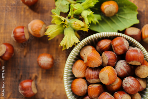 Hazelnuts close-up in a green cup on a wooden table. Whole nuts with green leaves. Fresh harvest of hazelnuts. organic ripe hazelnuts. Healthy fats.Hazelnuts harvest.view from above. 