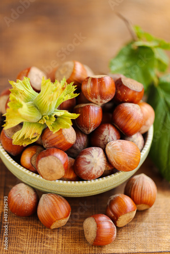 Hazelnuts close-up in a green cup on a wooden table. Whole nuts with green leaves. Fresh harvest of hazelnuts. Healthy fats.Hazelnuts harvest.view from above. 