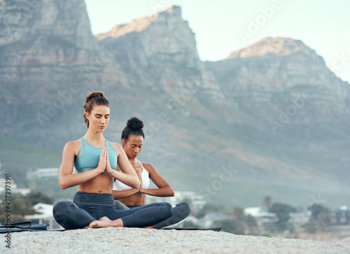 Yoga takes you on a wonderful journey. Shot of two sporty young woman practicing yoga together outdoors.