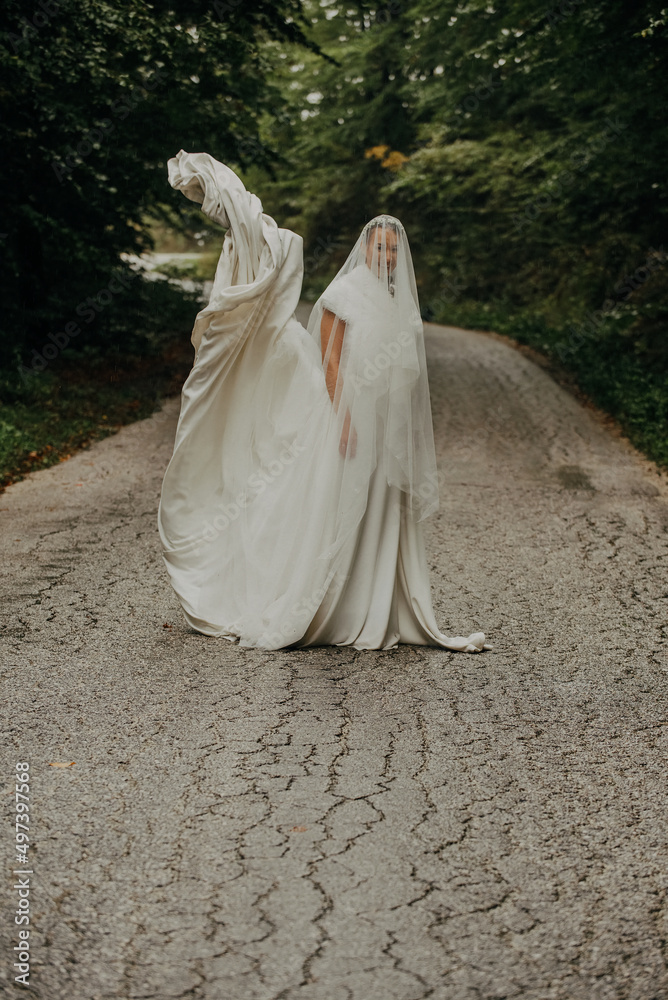 The bride is photographed in a wedding on a rainy day in a beautiful natural environment. Selective focus The bride is photographed in a wedding on a rainy day in a beautiful natural environment. Selective focus