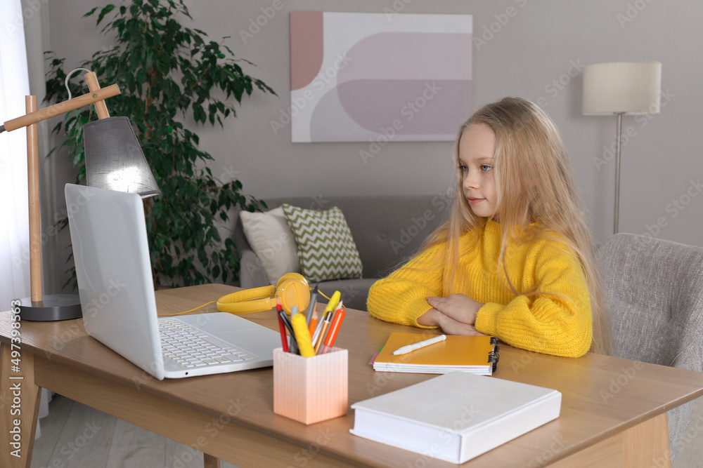 Cute little girl with modern laptop studying online at home. E-learning Cute little girl with modern laptop studying online at home. E-learning