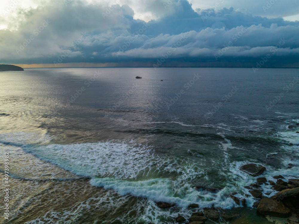 Fototapeta premium Sunrise seascape with rain clouds on the horizon