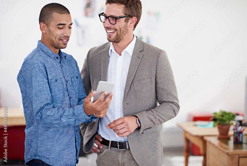 Obraz premium Another perfect job. Shot of two coworkers standing in an office looking at a digital tablet.
