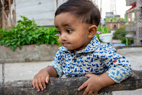 An infant child is standing and holding a dried bamboo and looking at the camera. Baby's smiley face on a beautiful afternoon at the rooftop.