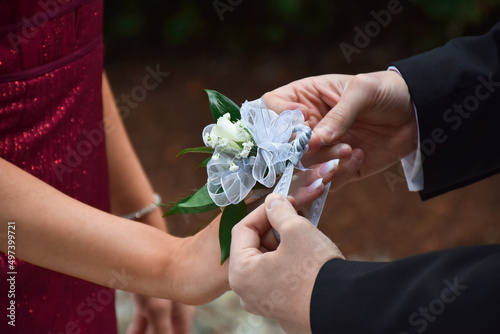 Photo Young man putting white rose corsage on his prom date hand
