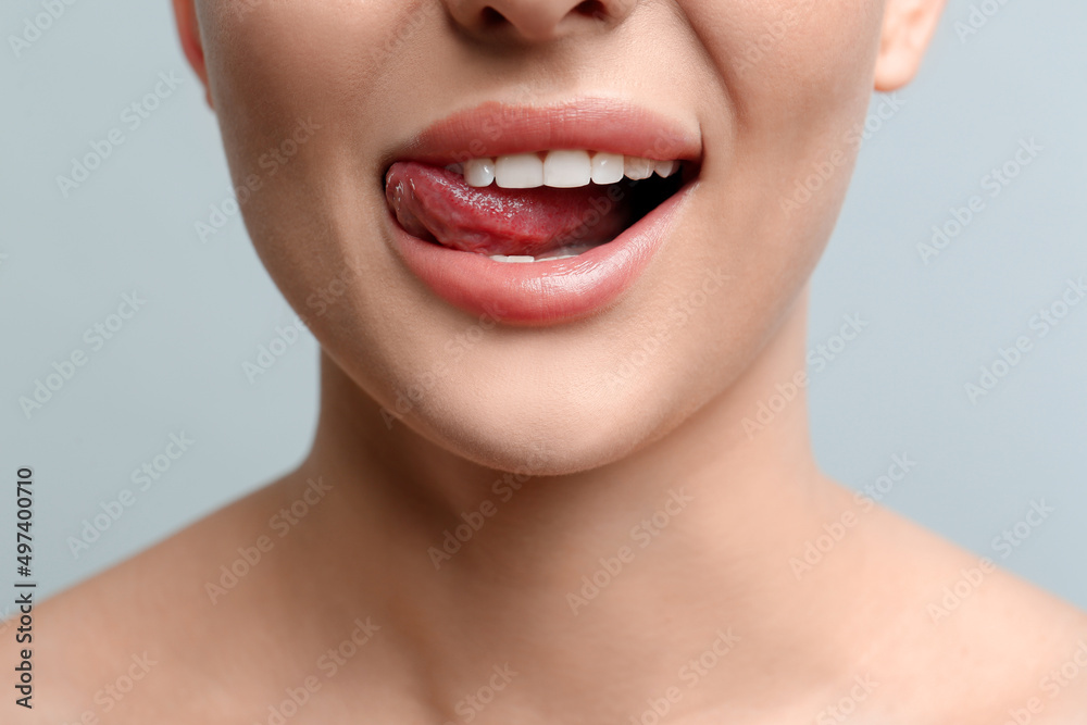 Obraz premium Woman licking her lips on light background, closeup