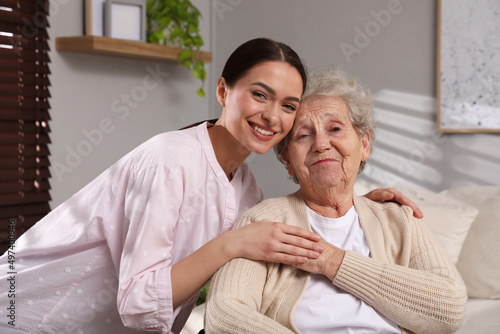 Portrait of young caregiver and senior woman indoors. Home care service