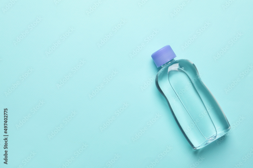 Bottle of baby oil on turquoise background, top view. Space for text Bottle of baby oil on turquoise background, top view. Space for text