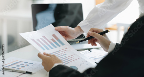 Close up team businesswoman studying statistics and holding a graph document by hand An office worker stood near the desk with a laptop. woman pointing finger