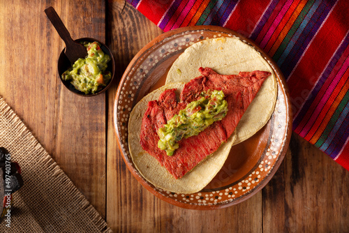Tacos de Cecina Enchilada con Guacamole. Salted, sun-dried pork or beef meat, seasoned with various spices and chili peppers, usually eaten in tacos photo