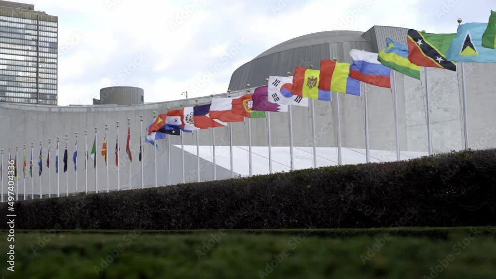 Flags flying in the wind, slow motion flags in front of United Nations in NYC. Russia flag, Poland flag and other flags waving slowly. UN security council in New York City